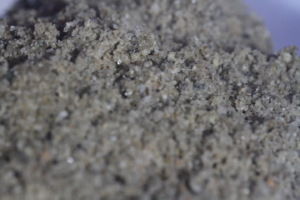 a macro photograph of sand with the individual grans clearly visible, some dark and some shiny and reflective